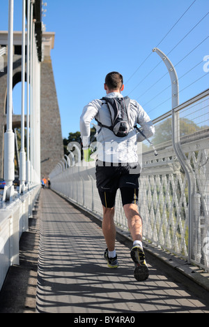 A male jogger crossing Bristol`s famous Clifton suspension Bridge on a fine sunny morning. Stock Photo